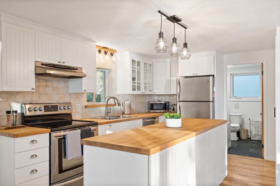 Bright kitchen with butcher-block island, stainless appliances and pendant lights